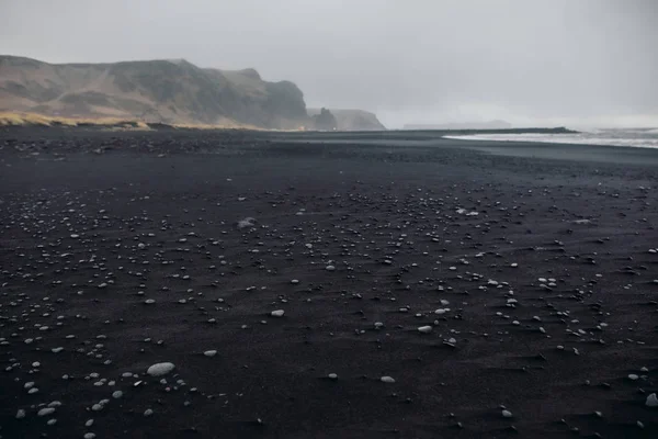 Seashore with black sand and stones — Stock Photo, Image
