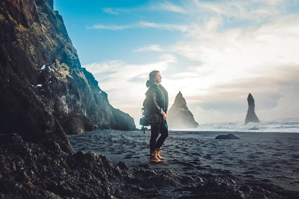 Young woman standing on rocky seashore — Stock Photo, Image