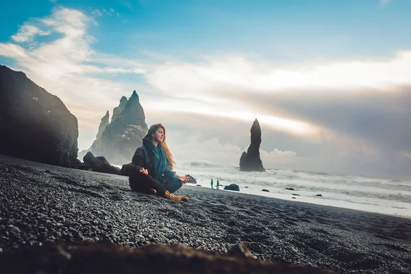 Young woman sitting on rocky seashore — Stock Photo, Image
