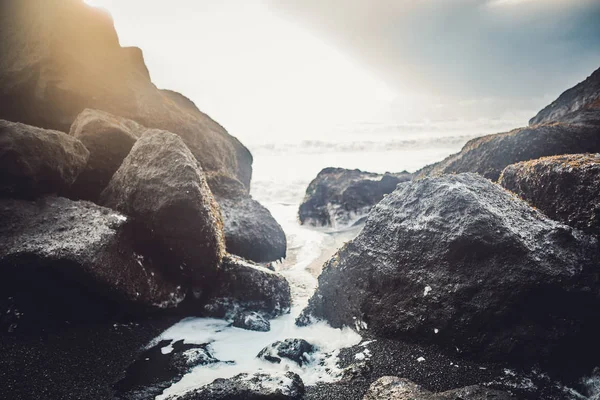 Svart lavastenar på stranden — Stockfoto