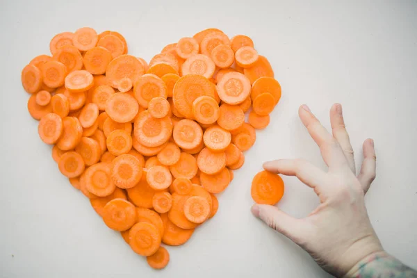 Tangan membuat jantung dari irisan wortel — Stok Foto