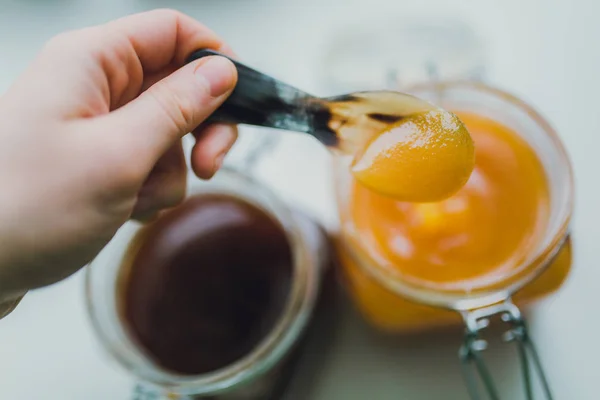 Hand holding metal spoon with honey — Stock Photo, Image