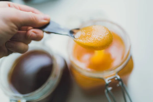 Hand holding metal spoon with honey — Stock Photo, Image