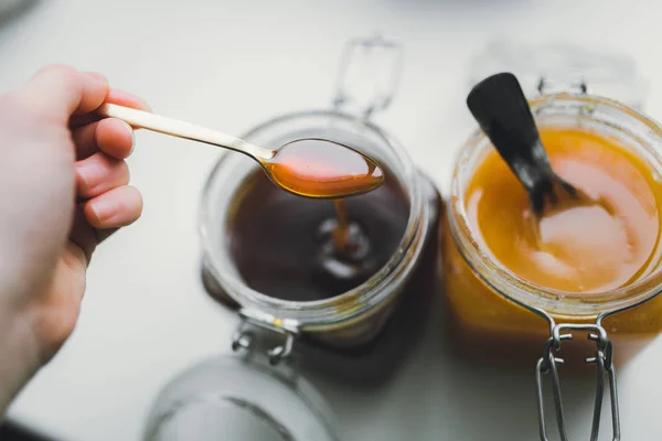 Mano sosteniendo cuchara dorada con miel —  Fotos de Stock