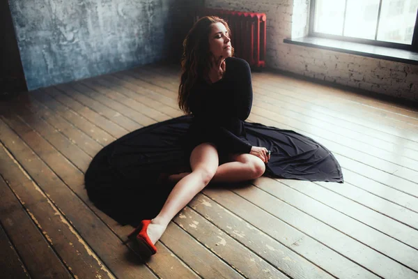 Frau in schwarzem Kleid am Boden — Stockfoto