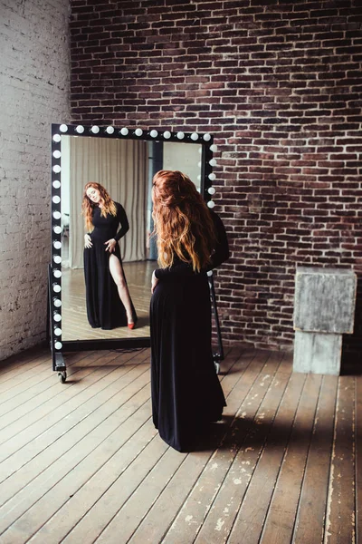 Frau in schwarzem Kleid neben Spiegel — Stockfoto