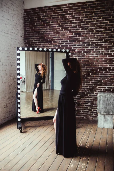Mujer en vestido negro cerca del espejo — Foto de Stock