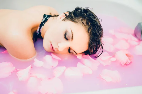 Mujer en agua rosa y pétalos — Foto de Stock