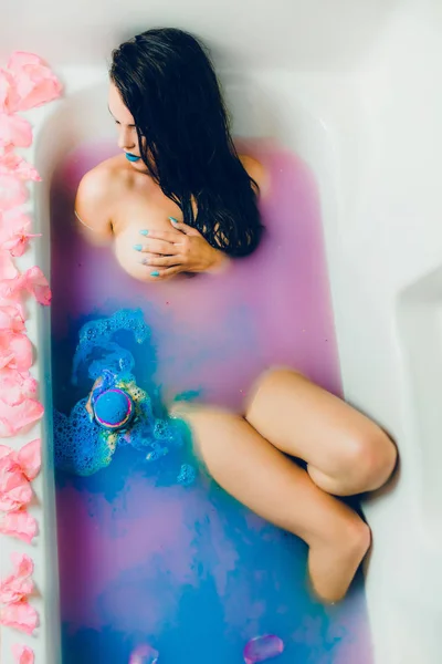 Vrouw in blauwe water en bloemblaadjes — Stockfoto