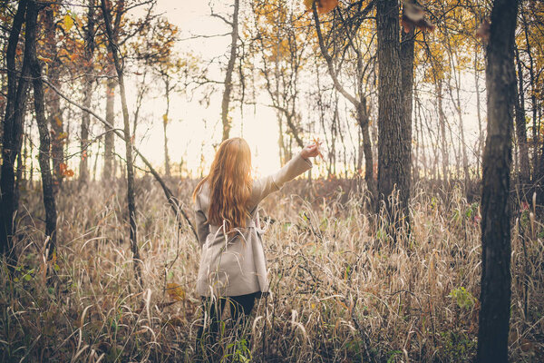 Portrait of cute redhead woman in coat at autumn forest
