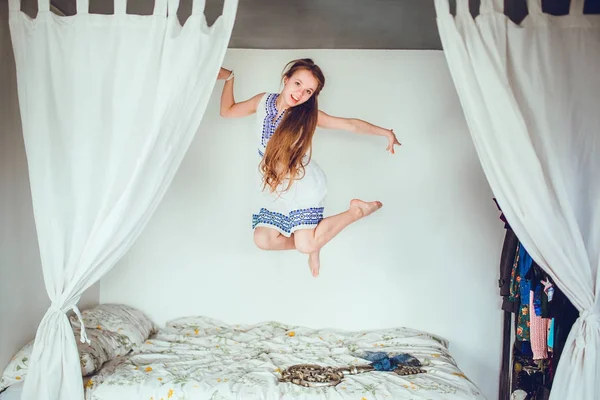 close-up of attractive girl jump in bed on room background
