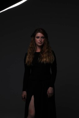 koyu arka plan üzerinde siyah elbiseli genç güzel kızıl saçlı kadın