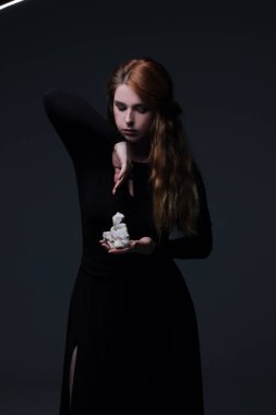 Deniz taş koyu arka plan üzerinde tutarak siyah elbiseli genç güzel kızıl saçlı kadın portresi