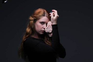 Deniz taş koyu arka plan üzerinde tutarak siyah elbiseli genç güzel kızıl saçlı kadın portresi