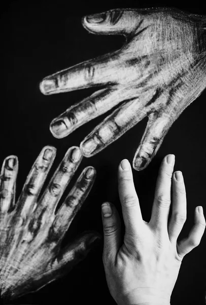 stock image close-up of female hand touching picture of hands on dark background, black and white