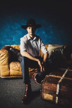 Oda arka plan, kahverengi kanepe üzerinde genç yakışıklı adam portresi