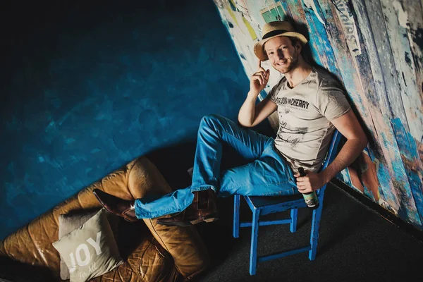 Retrato Joven Hombre Guapo Sosteniendo Botella Cerca Sofá Marrón Fondo — Foto de Stock