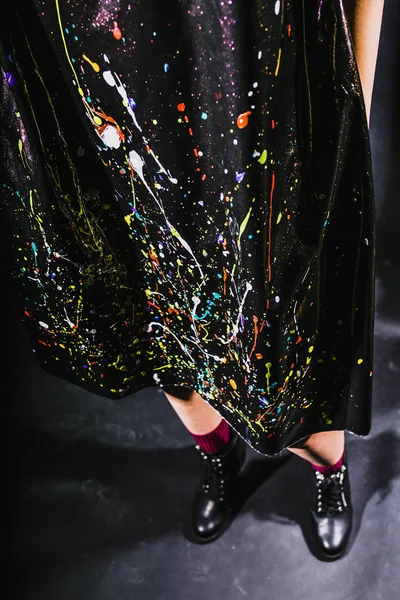 close-up of fashion black dress with colorful paint at black studio background
