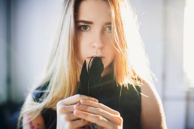 portre genç Kızıl saçlı kadının siyah saten elbise siyah karga tüy holding