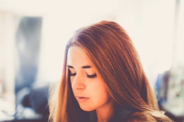 Genç Moda kadın kapalı gözler ve bulanık arka plan üzerinde kırmızı saç portresi