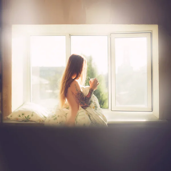 年轻裸体女人的肖像与纹身和长红头发喝咖啡附近的窗口早晨 — 图库照片