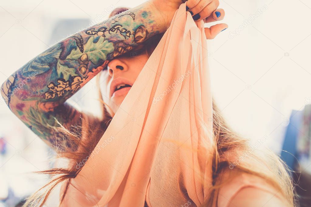 portrait of young fashion woman with red hair and tattoo on hand on blurred background