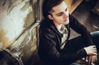 loft tarzı oda katta oturan siyah giysili genç moda adam portresi. 