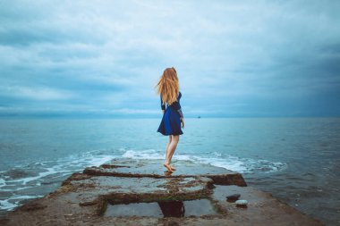 mavi elbiseli deniz kıyısında bulutlu gün açık dans dövme ile şirin Kızıl saçlı kadın