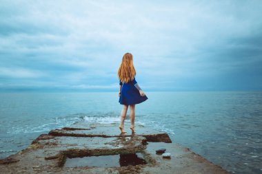 mavi elbiseli deniz kıyısında bulutlu gün açık dans dövme ile şirin Kızıl saçlı kadın