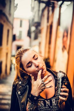 moda Kızıl saçlı kadın ile deri ceketli fotoğrafı dövme el üstünde tutan ve yeme black Ice-cream şehir sokak