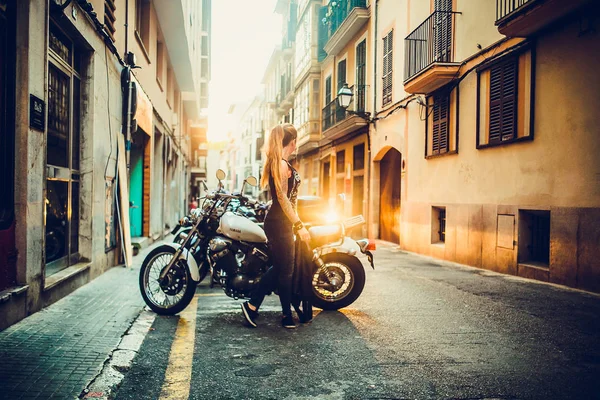 时尚红头发妇女的照片在手上有纹身的皮革夹克在城市街道上的摩托车在日落时间 — 图库照片
