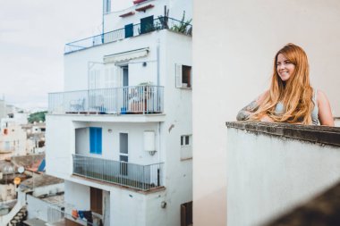 Beyaz binanın balkonunda el dövme ile sevimli genç Kızıl saçlı kadın fotoğrafı