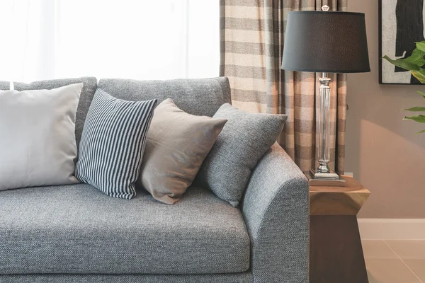 Řada polštářů na šedou pohovku s černými lampy v obývacím pokoji — Stock fotografie