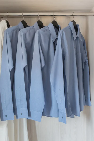 Row of blue color shirts hanging on rail — Stock Photo, Image