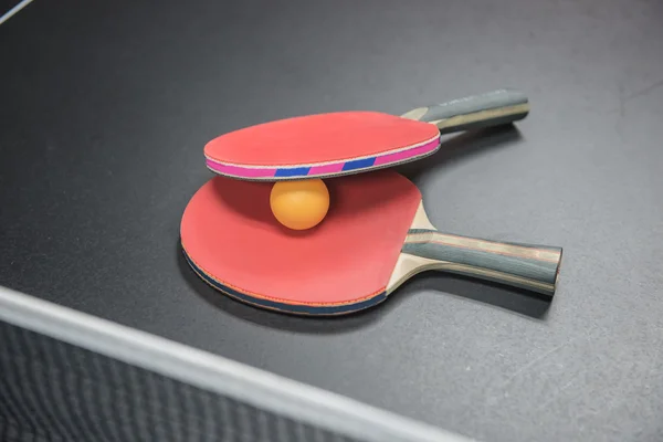 Raquette de ping-pong avec balle orange sur fond noir — Photo
