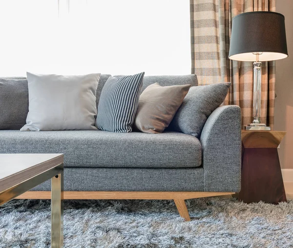 Reihe Kissen auf grauem Sofa mit schwarzer Lampe im Wohnzimmer — Stockfoto
