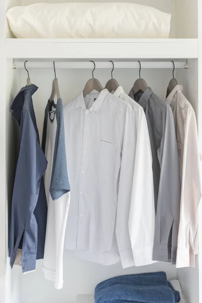 Одежда висит на рельсах в современном белом шкафу — стоковое фото