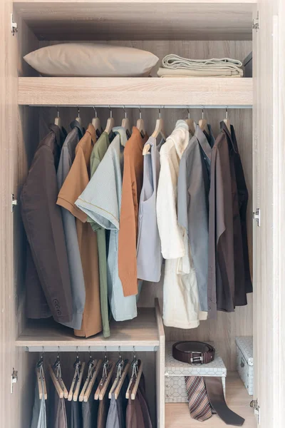 Kleidungsstücke hängen in hölzernem Kleiderschrank an Geländer — Stockfoto