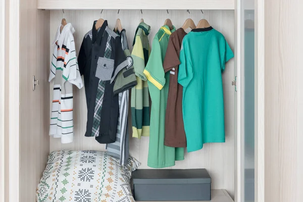 Kleidungsstücke hängen in hölzernem Kleiderschrank an Geländer — Stockfoto