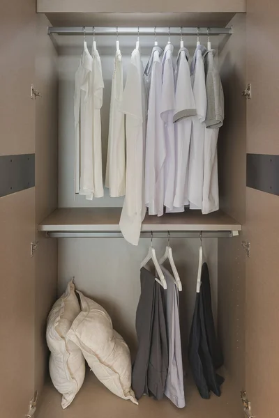 white shirts hanging on rail in wooden wardrobe