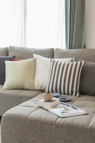 Taza de té en el libro con sofá moderno y conjunto de almohadas en moderno —  Fotos de Stock