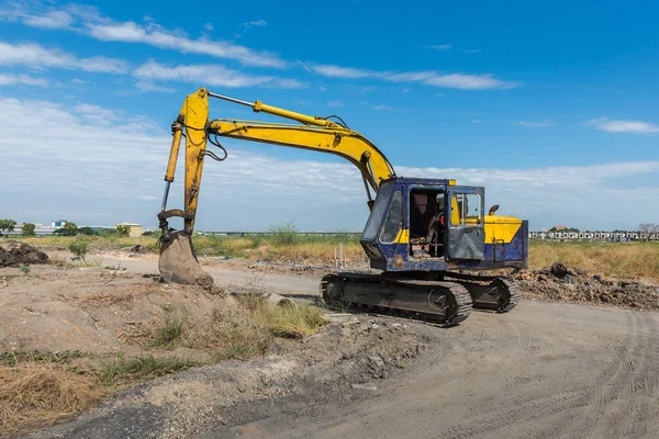 Sitio de construcción con excavadora amarilla sucia durante el trabajo —  Fotos de Stock