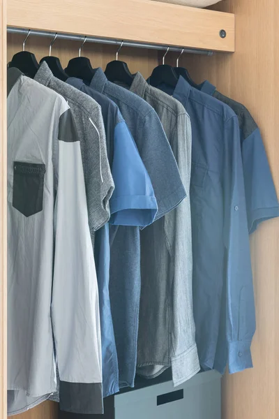 Одежда висит на поручне в деревянном шкафу — стоковое фото