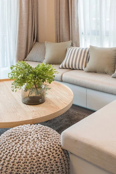 vast of plants on wooden round table in modern living room desig