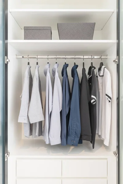 Одежда висит на поручне в деревянном белом шкафу — стоковое фото