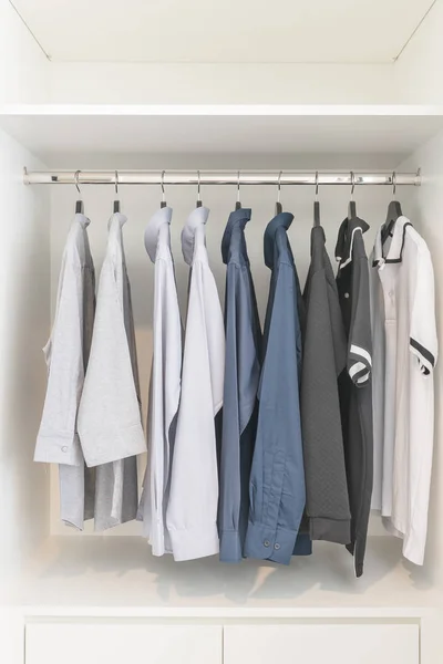 Clothes hanging on rail in wooden white wardrobe — Stock Photo, Image