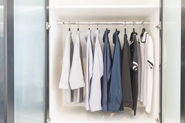 Roupas penduradas em trilho no guarda-roupa branco de madeira — Fotografia de Stock