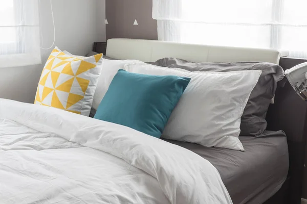 Oreillers colorés sur lit blanc dans la chambre moderne — Photo