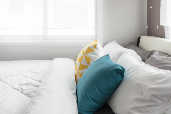 Kleurrijke kussens op witte bed in moderne slaapkamer — Stockfoto