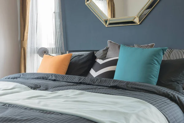 Almofadas coloridas na cama de cor escura no quarto moderno — Fotografia de Stock